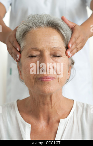 Senior woman having her temples massaged, cropped Stock Photo