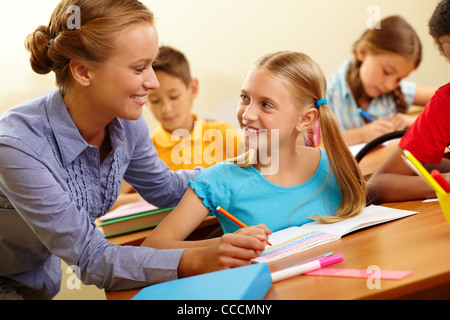 Portrait of smart girl and her teacher looking at each other at lesson in classroom Stock Photo