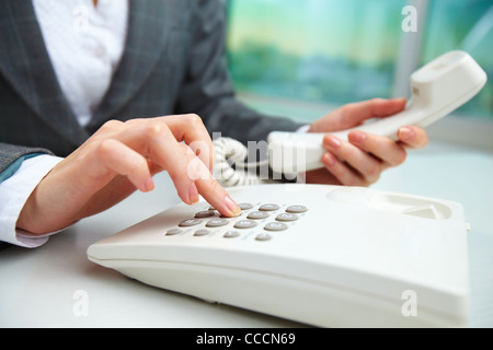 Female hand holding phone receiver and dialing number Stock Photo