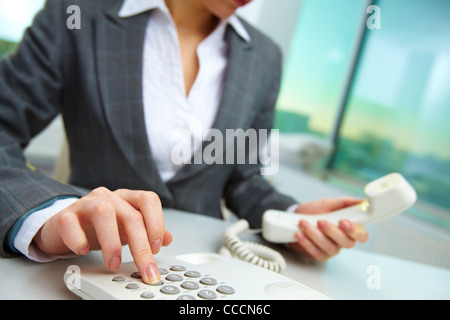 Female hand holding phone receiver and dialing number Stock Photo