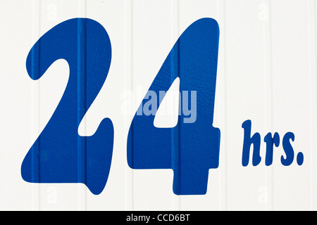 Twenty four hours sign painted on some white siding. Stock Photo
