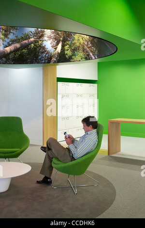 o2 headquarters tp bennett bath road slough berkshire uk 2009 interior view  showing man using mobile phone in green themed Stock Photo