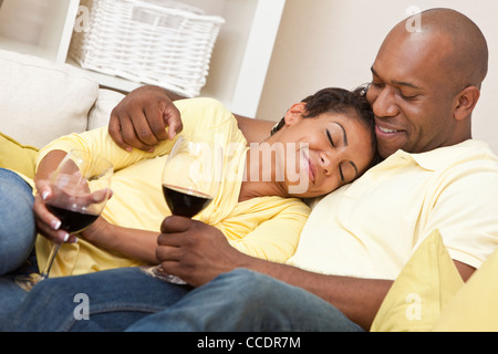 A happy African American man and woman couple in their thirties sitting at home together relaxing and drinking red wine Stock Photo