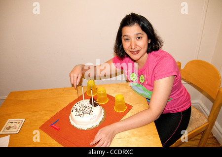 28 year old Hispanic Latino Woman Celebrates Birthday Sitting Next To Birthday Cake With Candles At A Wooden Table with birthday cake. Stock Photo