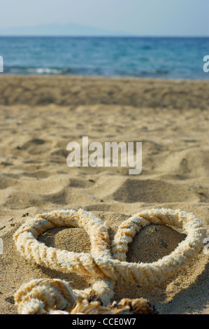 rope with a heart knot - beach sand background Stock Photo