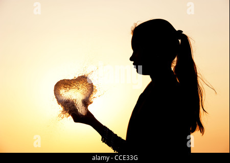 Indian girl holding a heart shaped burst water balloon. Silhouette. India Stock Photo