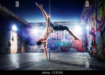 Young strong pole dance man on urban background. Stock Photo