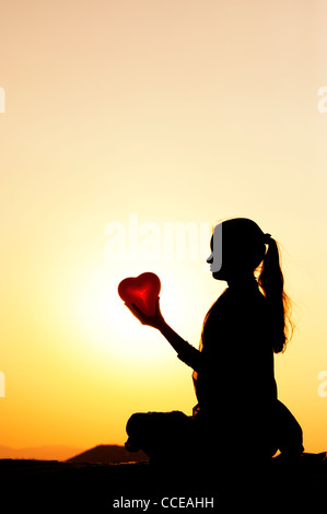 Indian girl holding a heart shaped balloon. Silhouette. India Stock Photo