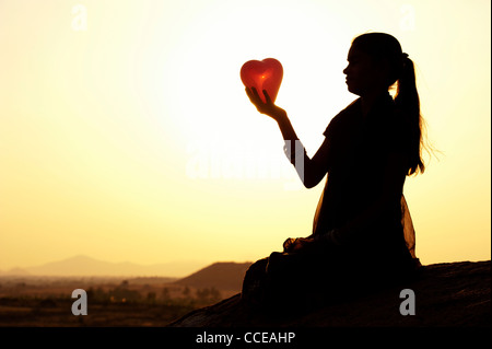 Indian girl holding a heart shaped balloon. Silhouette. India Stock Photo
