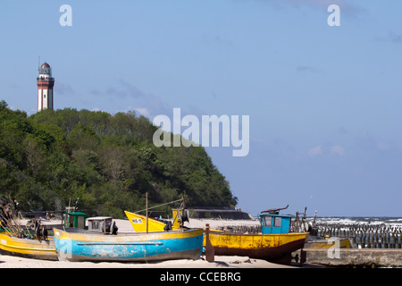 Fishing Boats on the beach in Niechorze. In the background, surrounded by trees you can see the lighthouse. Stock Photo