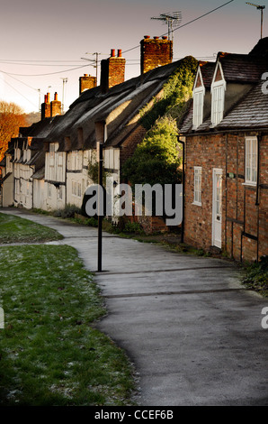 A wide empty public tarmac pavement leading to terraced thatched cottages Wendover Buckinghamshire UK Stock Photo