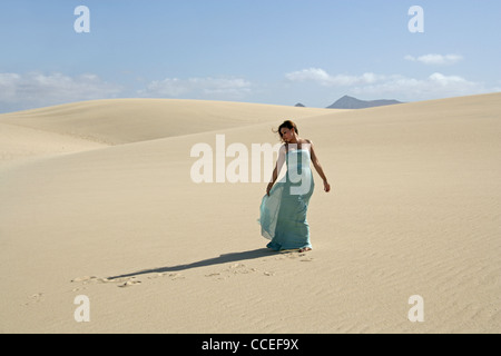 Indonesian Girl in a Turquoise Dress Walking on Sand Dunes, Fuerteventura, Canary Islands, Spain.
