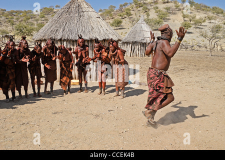 Himba women singing and man dancing in village near Opuwo, Namibia Stock Photo