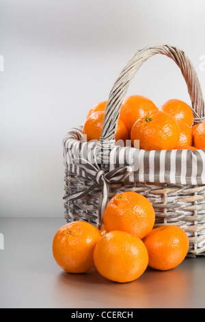 Basket and stack of fresh tangerines on silver background Stock Photo