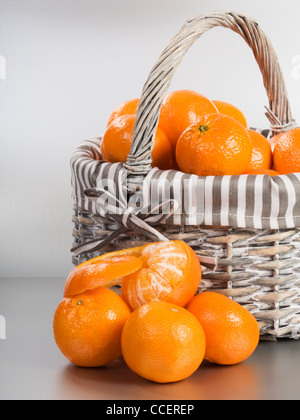 Basket and stack of fresh tangerines on silver background Stock Photo