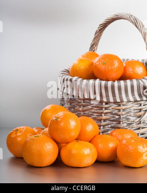 Basket and stack of fresh tangerines on silver background Stock Photo