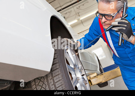 Elderly man working on car tire Stock Photo