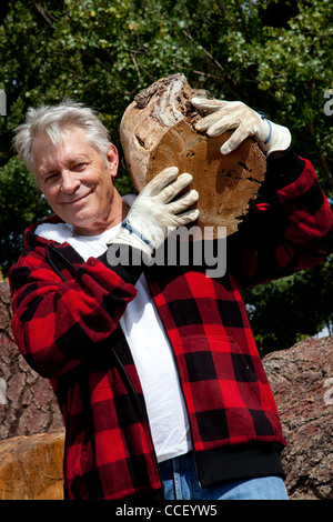 Senior man carrying firewood over his shoulders Stock Photo