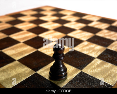 A pawn chess piece on an empty chessboard Stock Photo