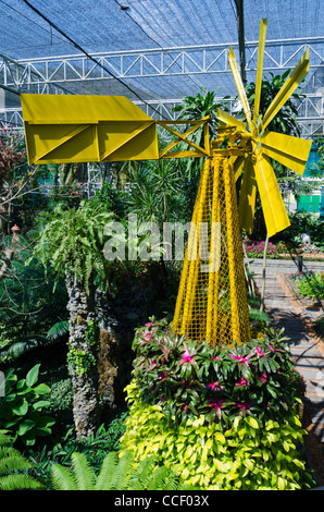 Yellow metal windmill sculpture inside huge greenhouse at Royal Flora Expo in Chiang Mai Thailand Stock Photo