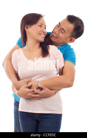 Loving Asian couple, hugging woman from behind smiling and looking at her isolated over white background Stock Photo