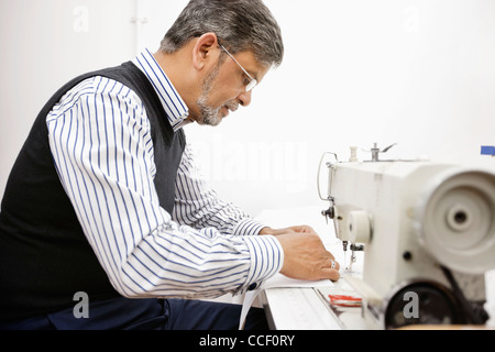 Profile of middle aged tailor using sewing machine Stock Photo