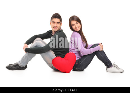 Young loving couple and a red heart shaped pillow isolated on white background Stock Photo