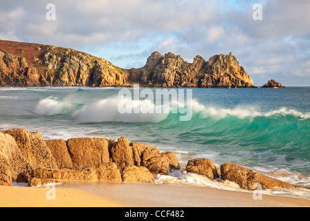 A breaking wave captured from Porthcurno Beach in Cornwall with Logan Rock in the distance Stock Photo