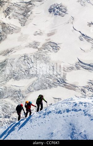 Mountain climbers ascending ice covered ridge in snow near summit of Mont Blanc in the French alps the highest peak in Europe Stock Photo