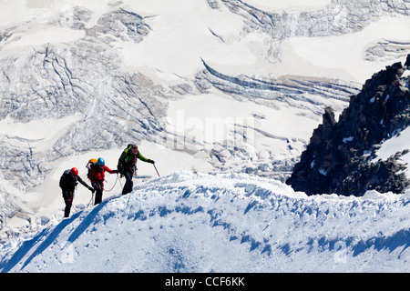 Mountain climbers ascending ice covered ridge in snow near summit of Mont Blanc in the French alps the highest peak in Europe Stock Photo