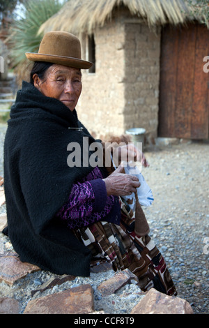 An Aymara woman weaves on a traditional hand loom in Huatajata on the Bolivian shore of Lake Titicaca. Stock Photo