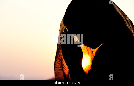 Indian teenage girl praying at sunset covered by a veil. Silhouette. India Stock Photo