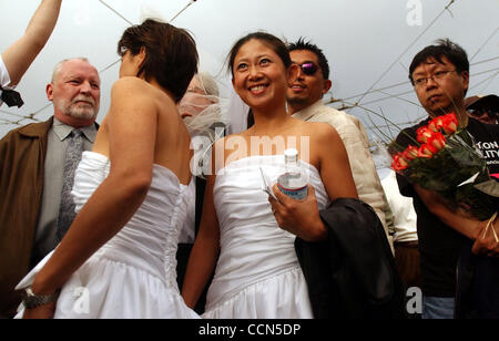 Making their way through the crowd in wedding dresses are Jeanne Fong, left, and her partner for 10 years Jennifer Lin, at the rally at Castro and Market Streets in San Franciso, Calif. Thursday, August 12, 2004. The rally was in protest to the California Supreme Court's decision ruling that Mayor G Stock Photo