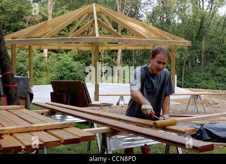 Sep 02, 2004 - Delhi, Ohio, USA - Covedale resident DAN STRUCKER, employee of Structure Building and Design, stains cedar planks that will be used to complete the new Delhi Park shelter house, under construction, in the background. The new structure will replace a former shelter house the caught fir Stock Photo