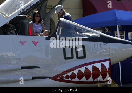 Summer Kimpark (left) laughs as her son Colton, 2, crawls in a 1960 era F-8 Crusader as Janelle Sahr (right)  of the USS Hornet Museum talks about the plane during the Peanut Butter and Jam Festival on Saturday September 11, 2004 in San Pablo, Calif.  Hundreds of people came out for the food, mercha Stock Photo