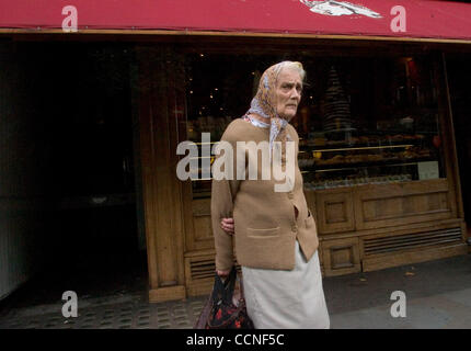 Oct 05, 2004; London, UK; An elderly woman in headscarf and shawl cardigan with her shopping bags on the streets of London, waits for the bus. Stock Photo