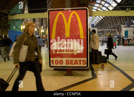 Oct 05, 2004; London, UK; A traveller at a train station passes a large Mc Donalds advertisement. Fast food is popular all over the world. Burgers and fries have high cholestoral and fat and are major causes of obesity in the developed world. Stock Photo