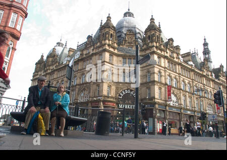 Oct 05, 2004; Leeds, UK; Old victorian building in the town centre, 'The Leeds City Market' has fresh fruit vegetables and meats daily. Elderly couple sit on a bench watching time to by. Stock Photo