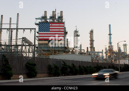Oct 18, 2004; Long Beach, CA, USA; The Conoco philips Oil Refinery at Carson nr Long Beach California with large stars and stripes USA flag hanging next to the huge chimmney smokestacks. The refinery has security fence with barbed razor wire around it. Security has been increased at refinerys across Stock Photo