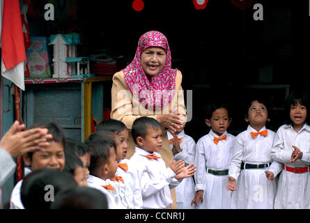 JAKARTA,  INDONESIA  NOVEMBER 29, 2004    Endrizaemi, known as  'Ibu Haji', guides kindergarten students singing in front of an ex-garage made into a school founded by her foundation, Pelita Dhu'afa, at Cilincing area. Besides working as the head of public elementary school, SD Negeri 03 Marunda, sh Stock Photo