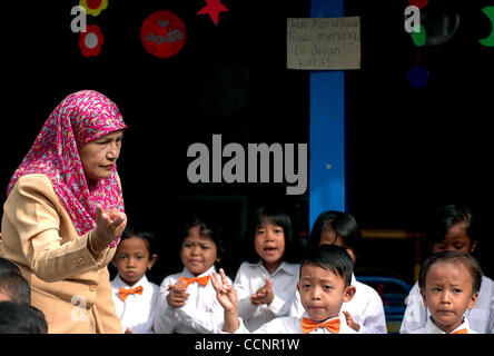 JAKARTA,  INDONESIA  NOVEMBER 29, 2004    Endrizaemi, known as  'Ibu Haji', guides kindergarten students singing in front of an ex-garage made into a school founded by her foundation, Pelita Dhu'afa, at Cilincing area. Besides working as the head of public elementary school, SD Negeri 03 Marunda, sh Stock Photo