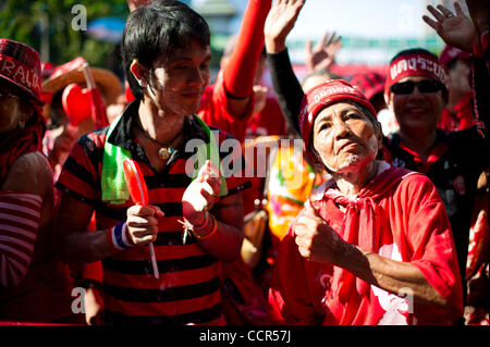 Red Shirts dance in front of UDD's stage during the Songkran festival at Ratchaprasong intersection in Bangkok. Red Shirts, also known as United Front of Democracy against Dictatorship (UDD), supporters of ousted Prime Minister Thaksin Shinawatra  celebrate the first of three days Songkran festival  Stock Photo