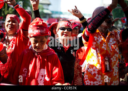 Red Shirts dance in front of UDD's stage during the Songkran festival at Ratchaprasong intersection in Bangkok. Red Shirts, also known as United Front of Democracy against Dictatorship (UDD), supporters of ousted Prime Minister Thaksin Shinawatra  celebrate the first of three days Songkran festival  Stock Photo