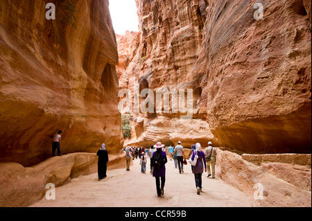 Tourists walk in a narrow passage that leads to El Deir also known as The Monastery. Petra is considered the most famous and gorgeous site in Jordan. Petra is located about 262KM to the south of Amman. Stock Photo