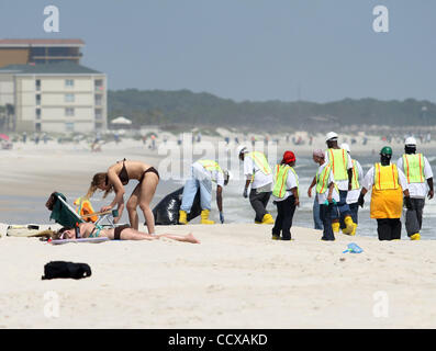 Members of a clean-up crew, searching for tar-balls and other debris, pass tourists and beach-goers on Dauphin Island, Alabama, on 5.14.10. The region has been preparing for the growing oil spill in the Gulf of Mexico after the Deepwater Horizon disaster. Stock Photo