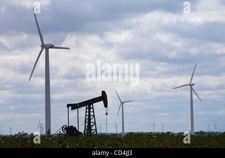 A lone oil pump jack sits in a cotton field with electric generating windmills outside Snyder, Texas. The farmers in the Texas panhandle have replaced the income of oil rigs with windmills. Stock Photo