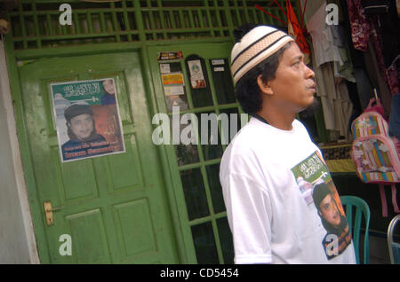 Chairul Anwar, a brother of Bali bomber Imam Samudra, stands near the bomber's portrait which reads, 'Only one word releases Imam Samudra' in his mother's home in Serang, Banten province, Indonesia, Nov 5, 2008. Three Indonesian militants on death row for the 2002 Bali bombings have exhausted legal  Stock Photo