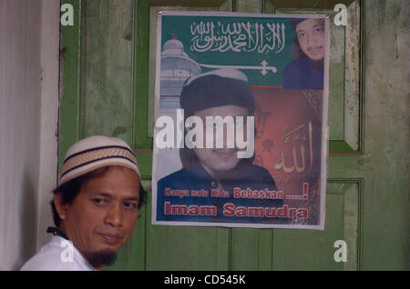 Chairul Anwar, a brother of Bali bomber Imam Samudra, stands near the bomber's portrait which reads, 'Only one word releases Imam Samudra' in his mother's home in Serang, Banten province, Indonesia, Nov 5, 2008. Three Indonesian militants on death row for the 2002 Bali bombings have exhausted legal  Stock Photo