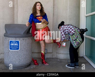 July 23, 2010 - San Diego, California, U.S. - Sara Valeespino, 20, from Baja, CA, lets her friend fix her shoe after hours of walking.  ''It's been a long day,'' Valeespino said.  Thousands attended Comic Con's costumed festivities in downtown San Diego on Friday.  Families, couples and kids - some  Stock Photo