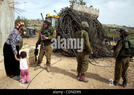 May 25, 2011 - Hebron, West Bank, Palestinian Territory - Israeli soldiers stand guard destroy agriculture land partially, and a Palestinian woman argue with the Israeli soldiers near the West Bank City of Hebron across the road from the Israeli settlement of Kiryat Arba on May 25, 2011. as a respon Stock Photo